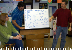 A group of three is presenting, using a whiteboard